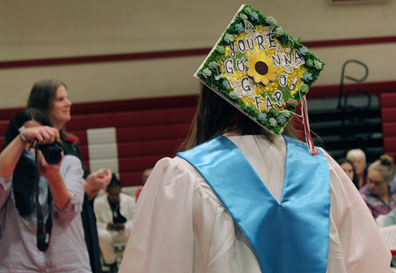 A person takes a picture of a graduate with a decorated cap