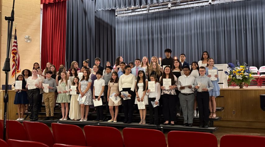 Students stand on stage holding certificates