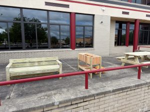 Two benches and a raised garden bed, all made of wood, sit on a patio.