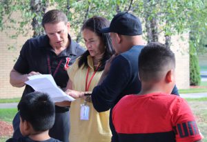 Three people look at a piece of paper as two children stand in front of them.