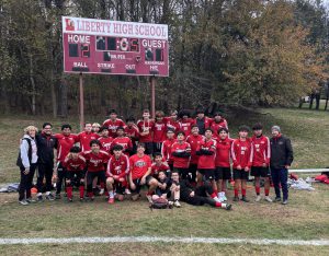 A soccer team poses in front of the scoreboard.