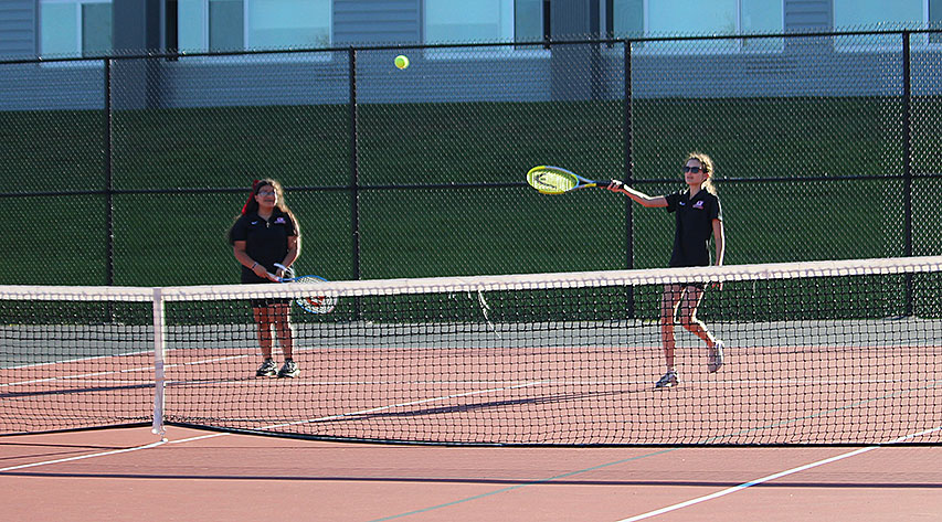 A tennis player returns a volley during a doubles match