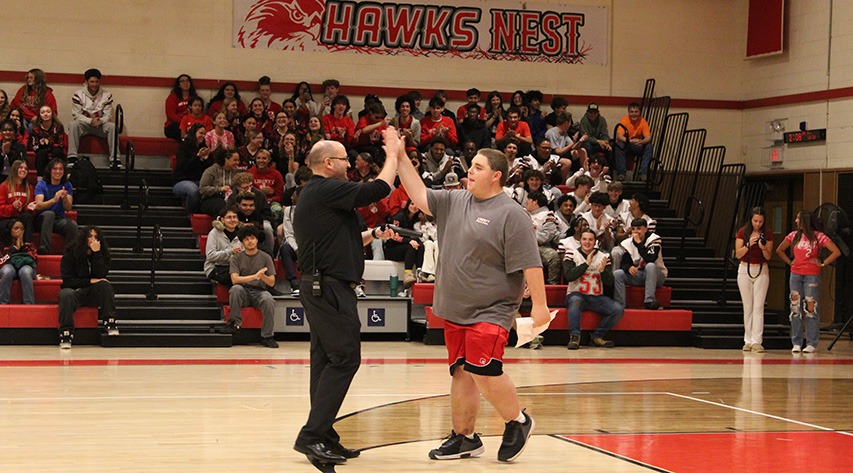 A student and principal high five on a basketball court