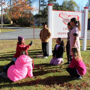 An adult shows students what side should be up on a bulb