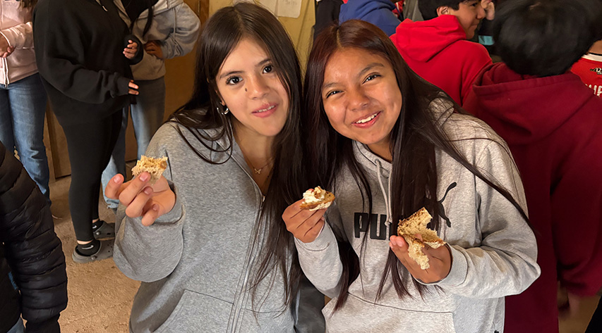 two students smile as they hold food