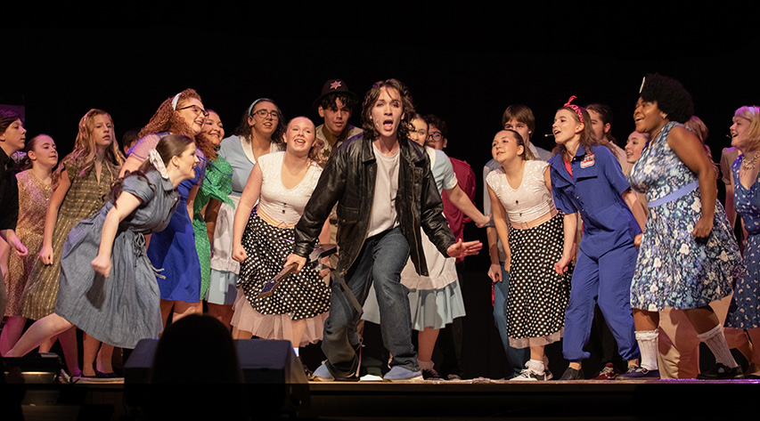 Students sing during a performance on stage
