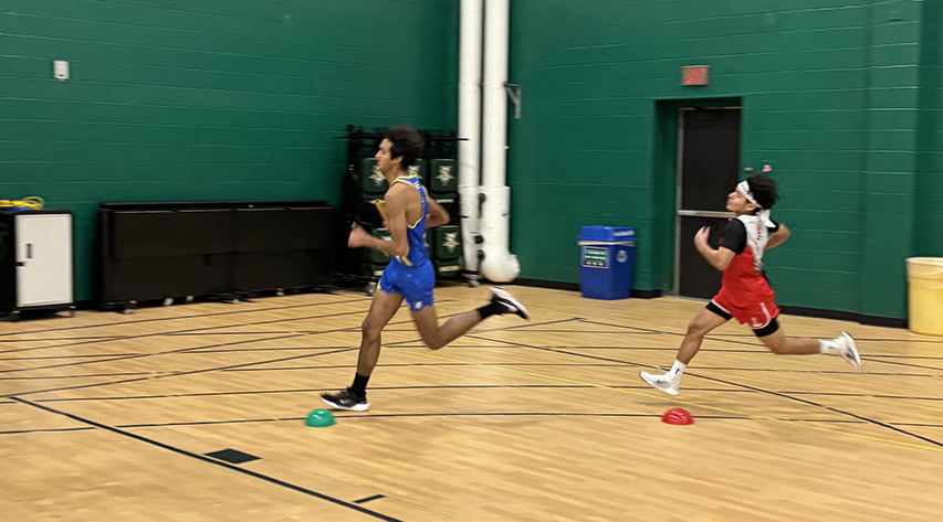Two runner turn the corner at an indoor track meet