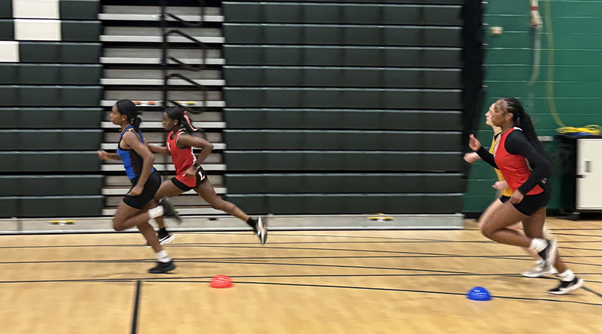 four runners turn a corner in an indoor track meet