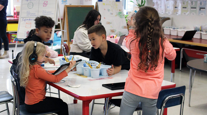 Young students work collaboratively at a table.