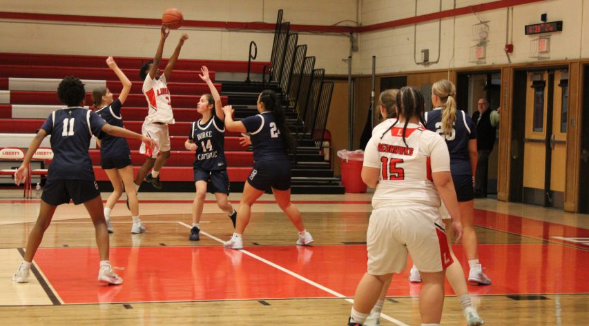 A Liberty player shoots a basket as opponents surround her
