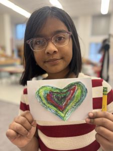 A student displays a painting of heart.