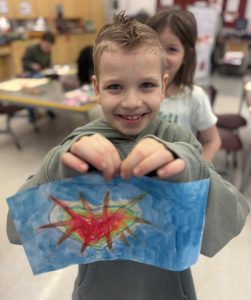 A student displays a painting of heart.