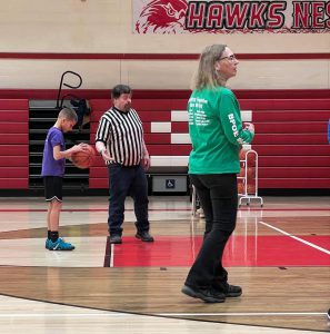 A student prepare to shoot a basket as a ref and another adult watches