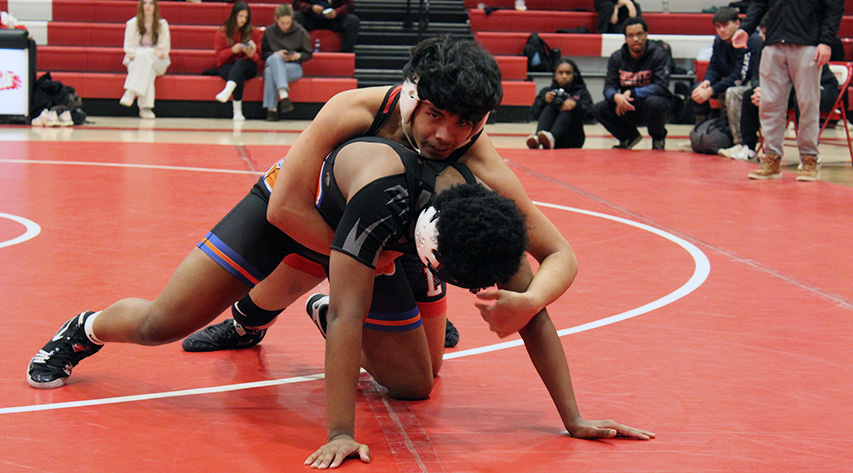 Two wrestlers compete on a mat.