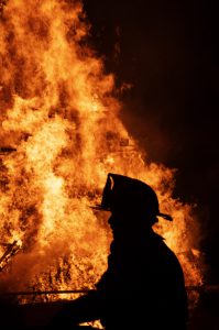 A firefighter is silhouetted by flame