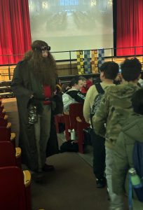 A teacher dressed as Hagrid welcomes students in to the auditorium
