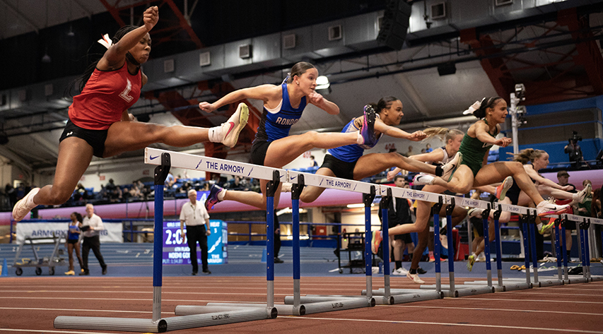 Athletes jump over hurdles during a race