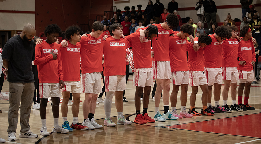 Liberty Redhawks players stand on the foul shot line as cheerleaders stand behind them.