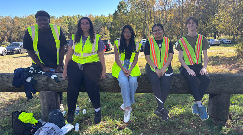 Five people in yellow vests sit on a bench