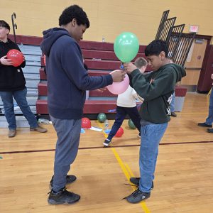 Two students tie balloons together.