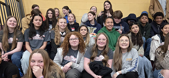 Students pose for a photo on bleachers.