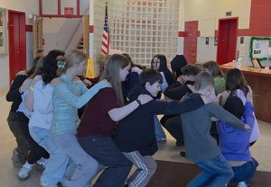 Students complete a team building exercise in the lobby of the middle school.