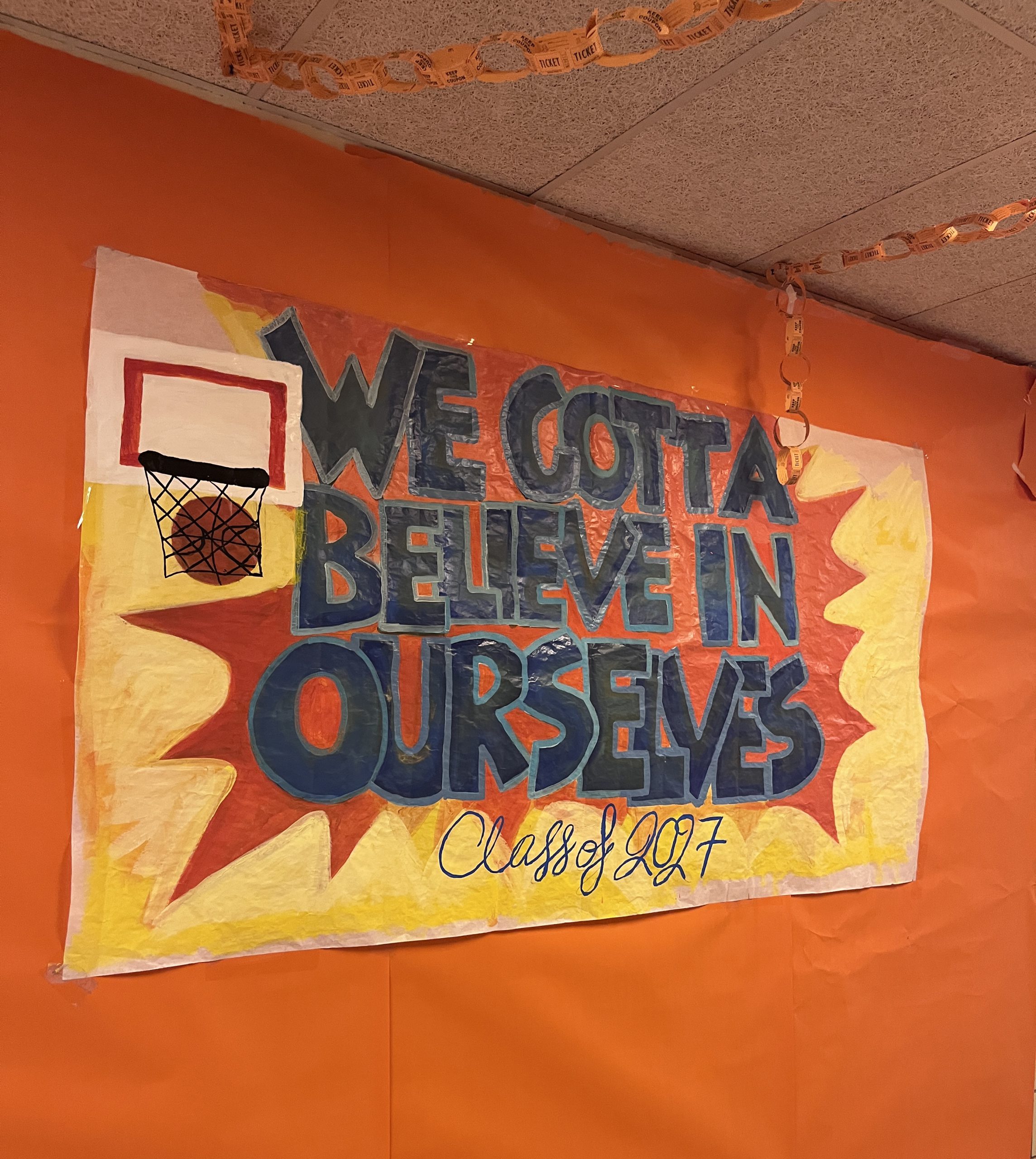 class of 2027-hallway-sign A sign reads we gotta believe in ourselves Class of 2027 in a Space Jam orange theme.
