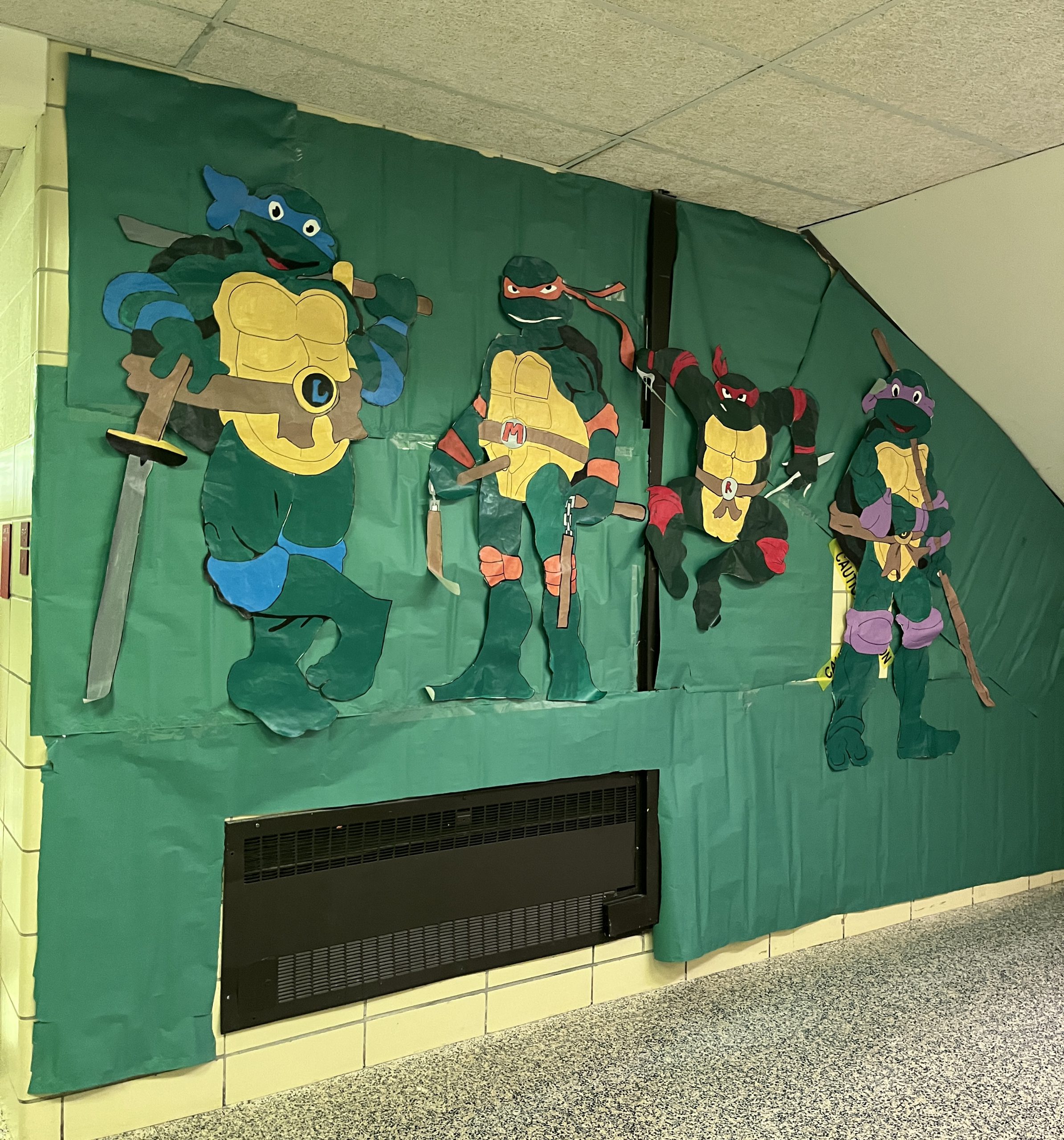 class of 2028-hallway-turtles Characters from the Teenage Mutant Ninja Turtles are displayed on a wall