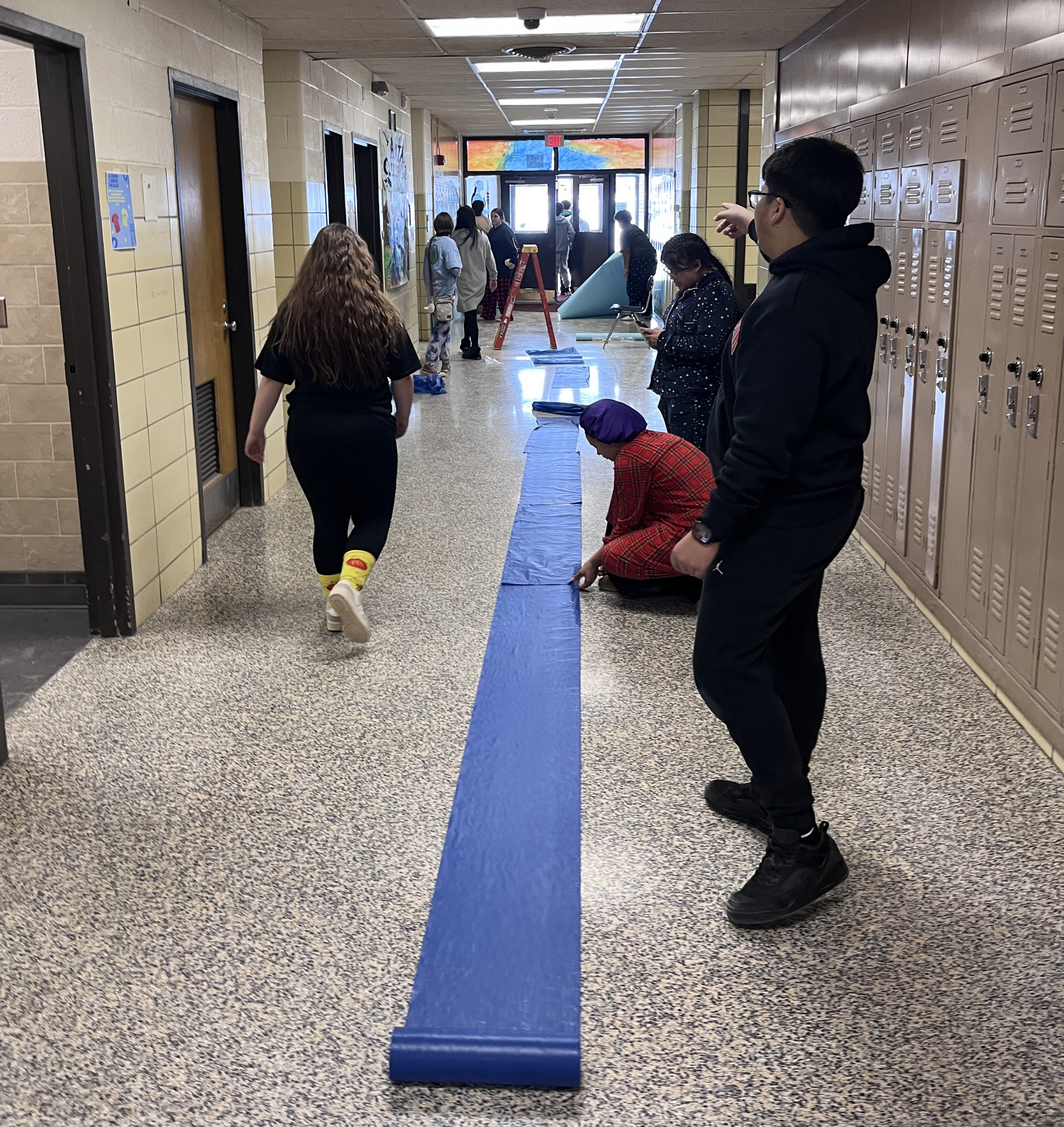 class of 2029 -hallway-film Students roll out blue vinyl cloth in a hallway