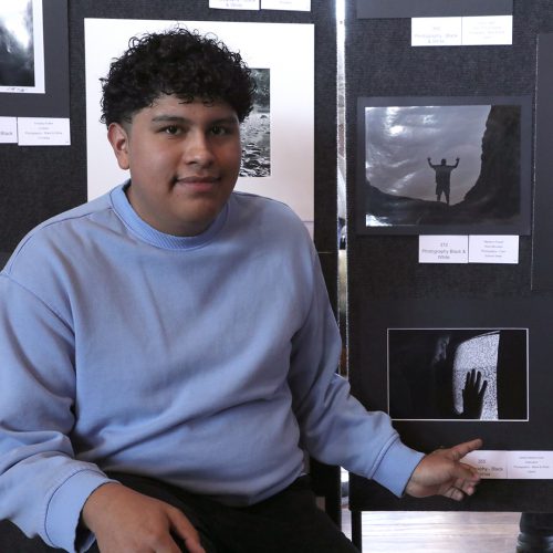 Carlos A student poses and points to his black and white photo