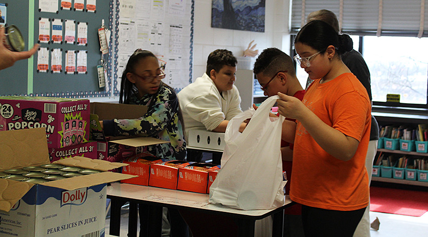 Students pack a bag with food.