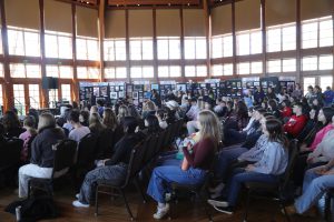 Students sit in an atrium at an art show.