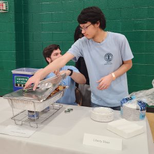 A student removes the cover from a buffet pan
