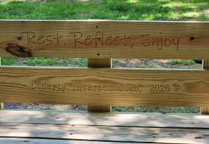 Rest Reflect Enjoy Liberty Interact Club 2026 is engraved into the back of a bench