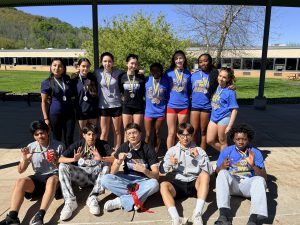 Track and field atheletes pose for a photo with medals around their necks.