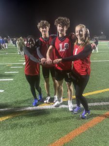 Four track athletes put their hands to the center and pose for a photo