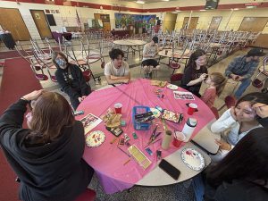 People paint children's faces at a round table covered with a pink table cloth