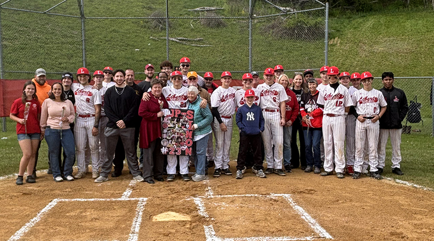 Baseball players and families pose near homeplate
