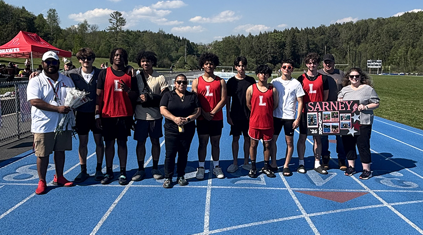 Track and field athletes and their families pose for a photo on a track.