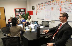 Educators sit at a conference table and speak during a professional development session