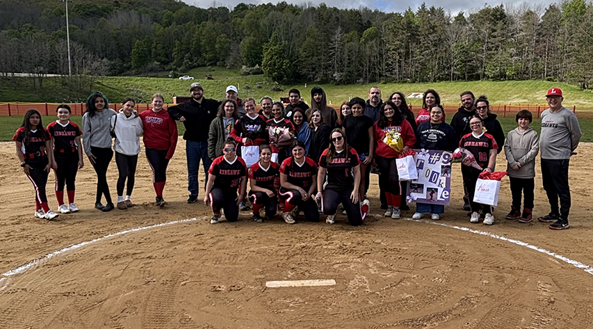 Softball players and their families pose on the softball pitcher circle