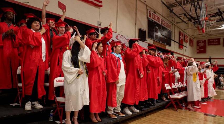 Students in red and white gowns turn their tassels on riders