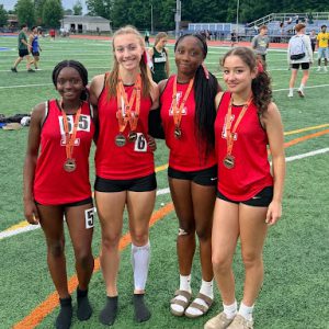 For members of the girls track team pose for a photo with medals around their neck