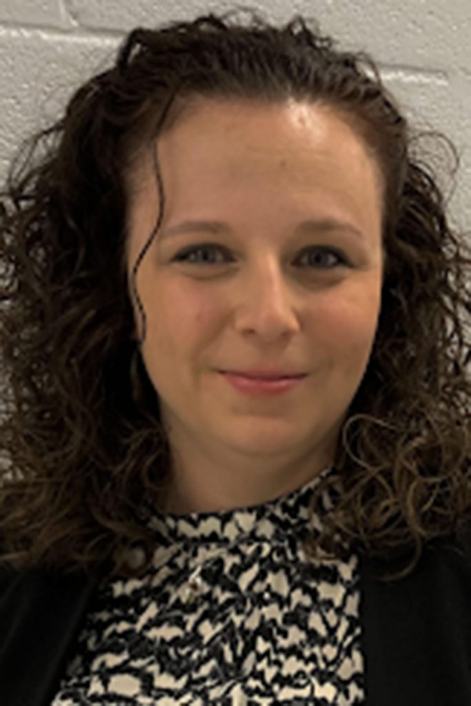 Headshot portrait of Lacy Jones, a smiling woman with dark, curly hair.
